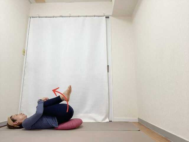 お尻の下にクッションを敷いて両膝を胸に抱えた仰向けの体勢