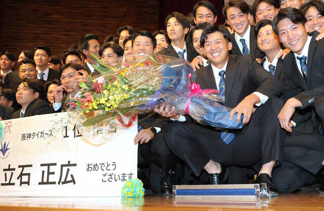 花束を手に野球部員らと笑顔を見せる創価大・立石正広(カメラ・清水 武)