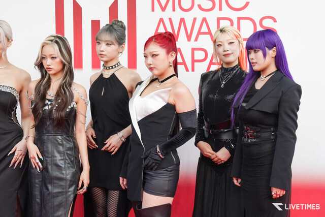 Six people in black outfits posing on a red carpet at a music awards event, with a white and red backdrop and LIVETIME logo visible at the bottom right.